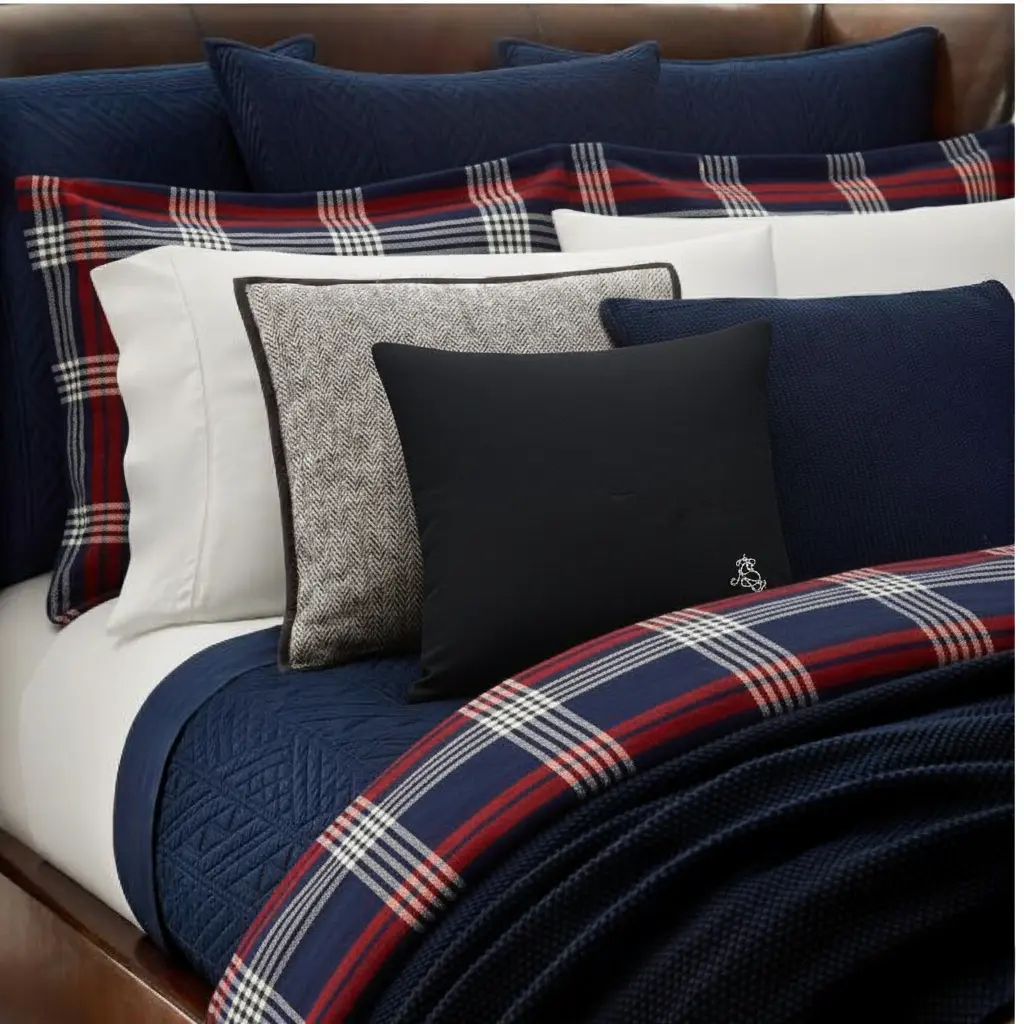 Midnight Embroidered Cotton Cushion – Styled in Bedroom Setting Midnight Embroidered Cotton Cushion styled on a bed with tartan linens and layered pillows – luxury bedroom decor.