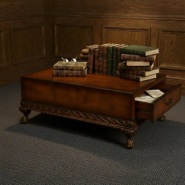 Dayton Coffee Table in mahogany with burl marquetry, carved vine apron, and brass-handled drawer, styled on a natural jute rug with antique books