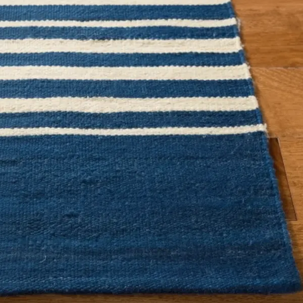 Montauk Regatta Stripe Wool Flatweave — Corner Detail Corner detail of navy-and-ivory regatta stripe wool flatweave rug showing tight kilim weave and bound edge on wood floor