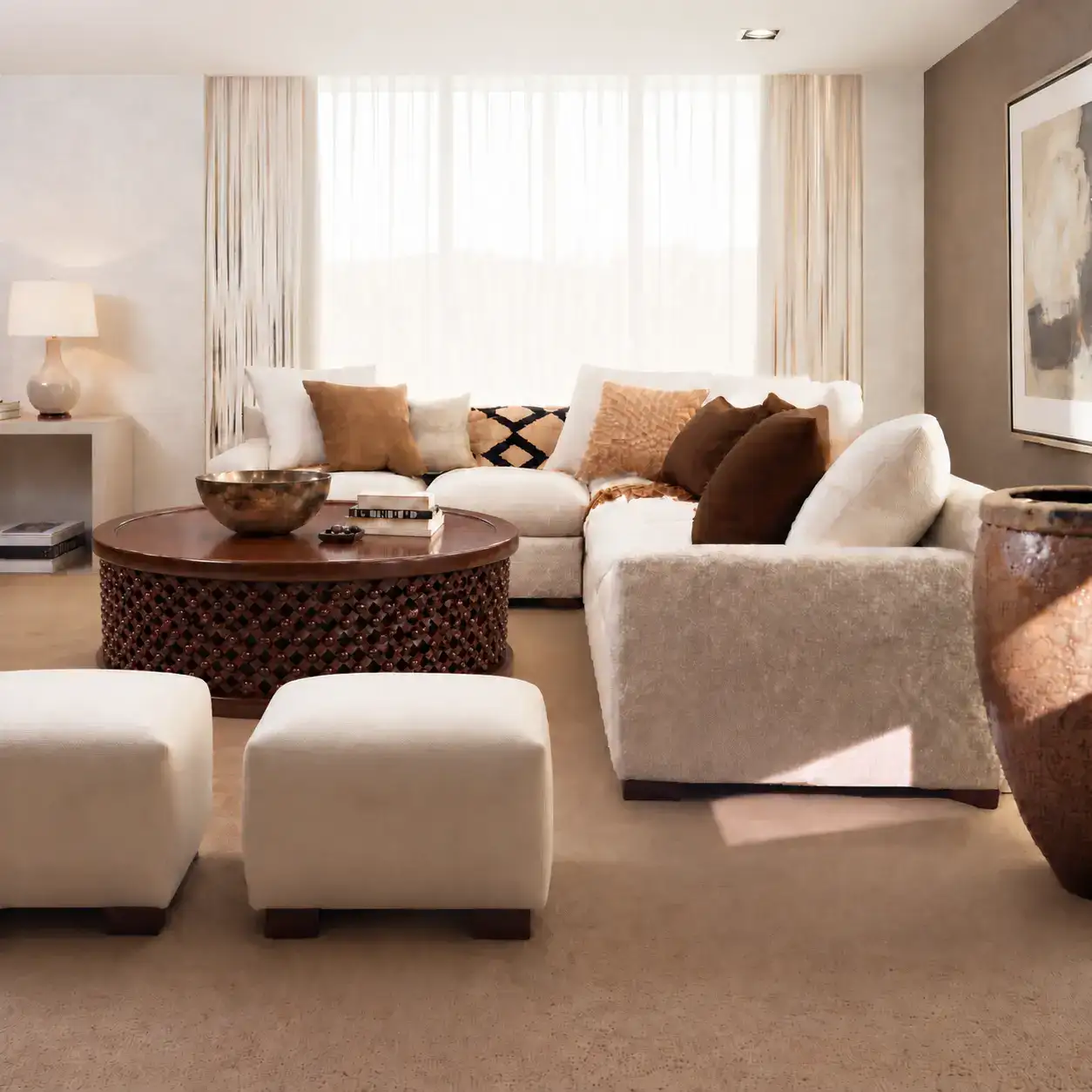 Bamileke Drum Table 4 Bamileke drum coffee table in brown mahogany styled in a cream living room with a sectional sofa, two ottomans and a bronze bowl