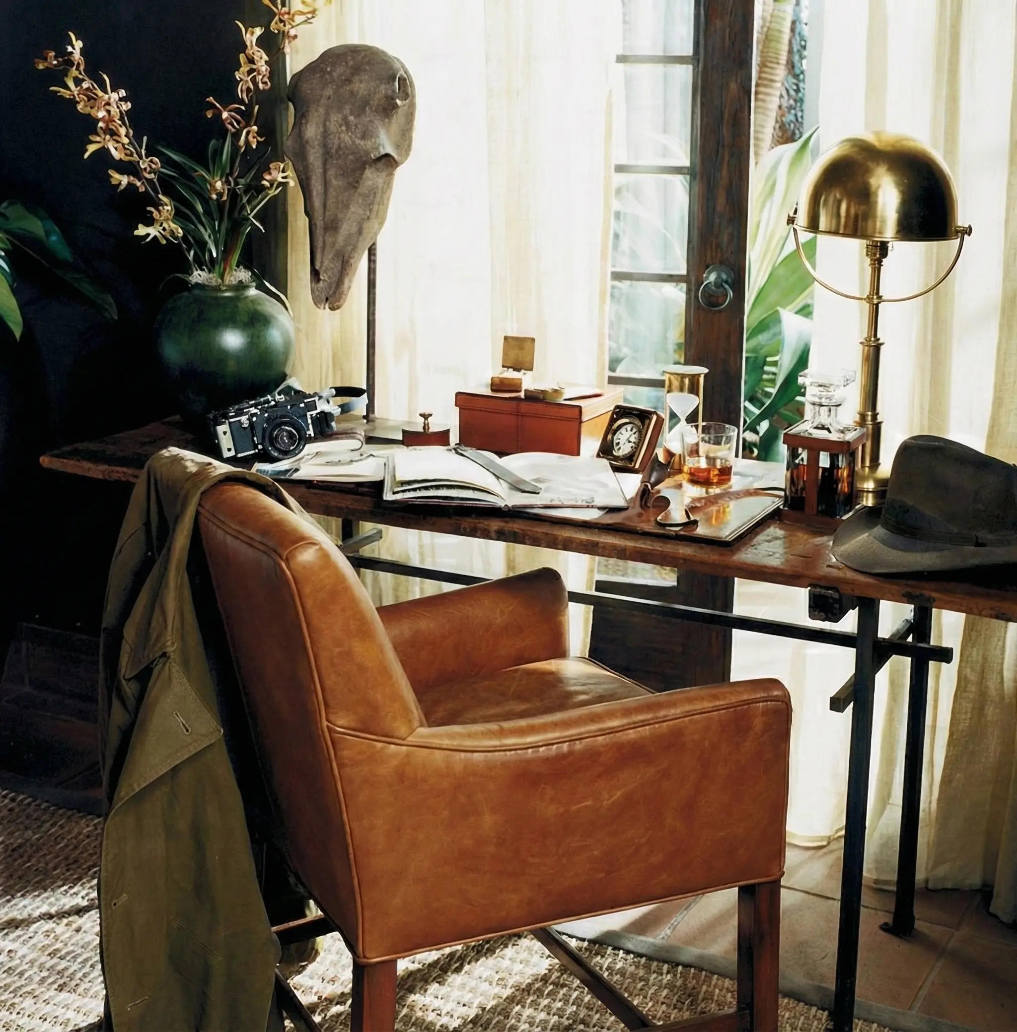 Close up of a luxury executive study in Saratoga featuring a vintage leather armchair, antique desk accessories, and a textured hand-woven wool rug