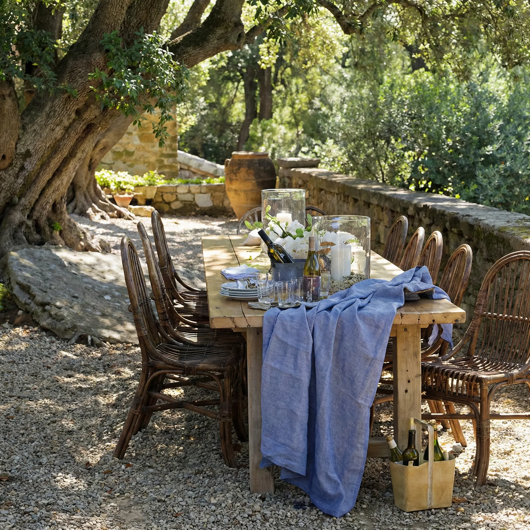 Rustic outdoor dining setting with woven chairs under olive trees, perfect for al fresco dining in the California hills