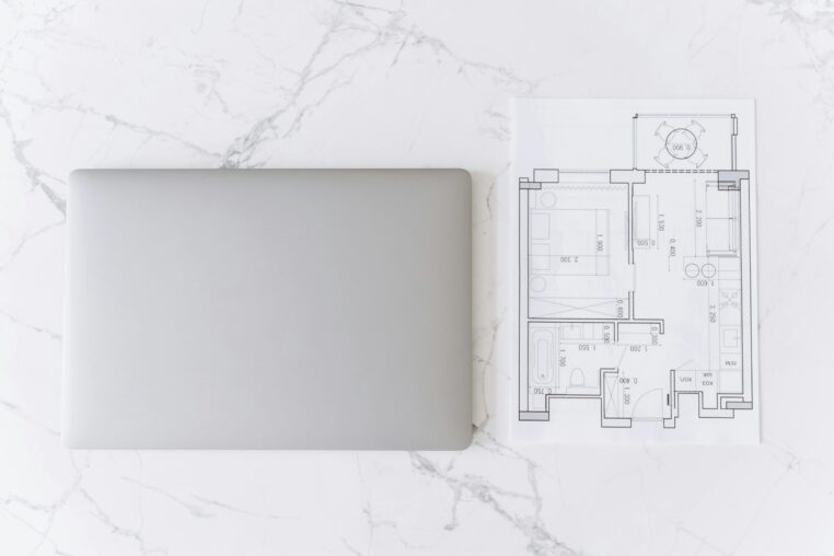 Laptop and architectural floor plan on a clean desk for interior planning