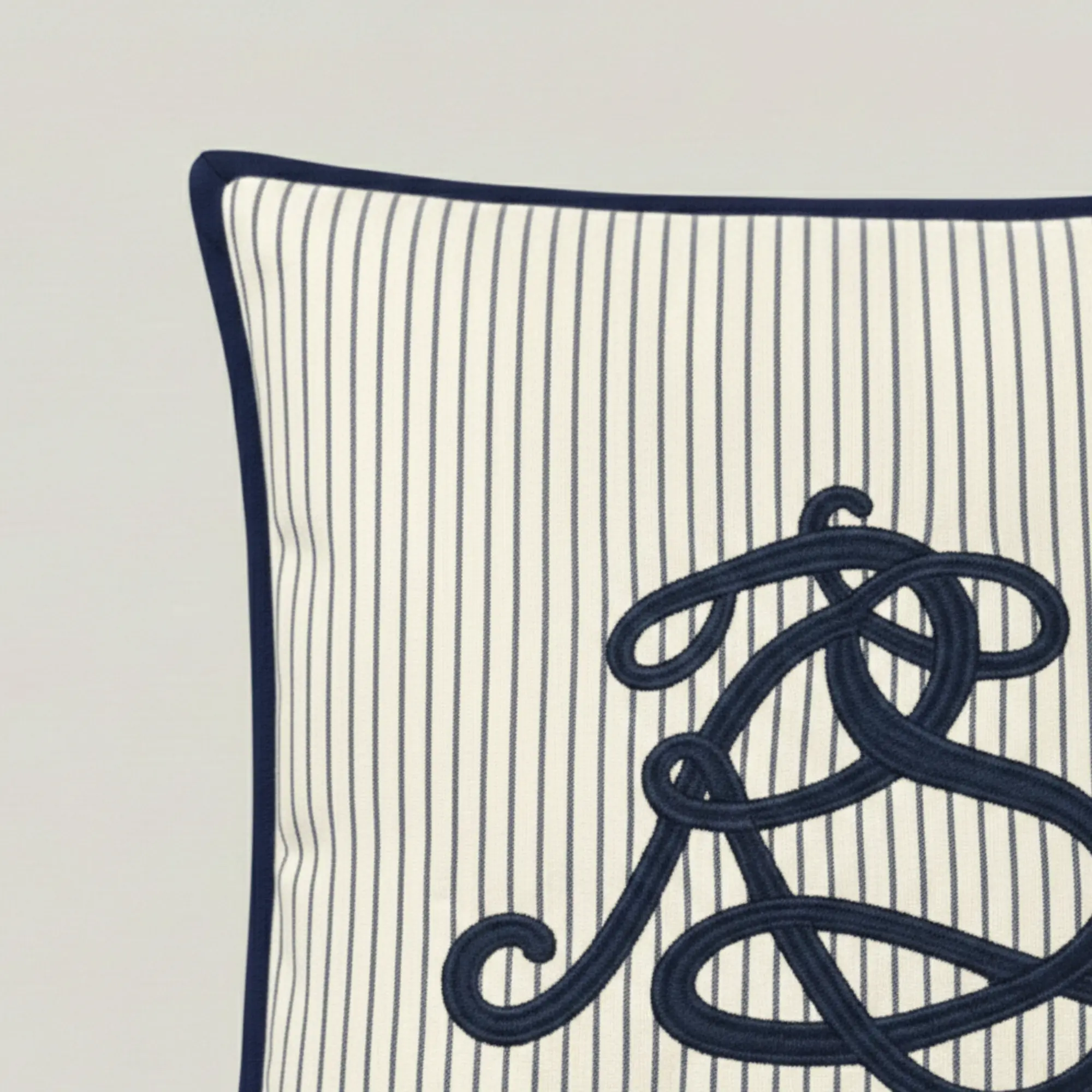 Close-up of embroidered script monogram on navy pinstripe cotton throw pillow
