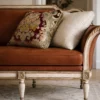 Layered tapestry and linen cushions on an antique upholstered sofa with carved wood frame are part of luxury furniture collection in Saratoga