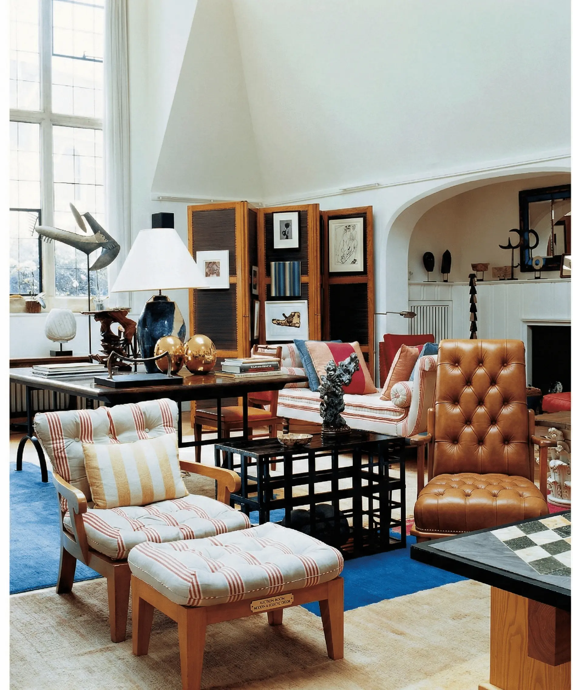 Studio living room with tall windows, screens, layered objects and textiles — large scale made intimate