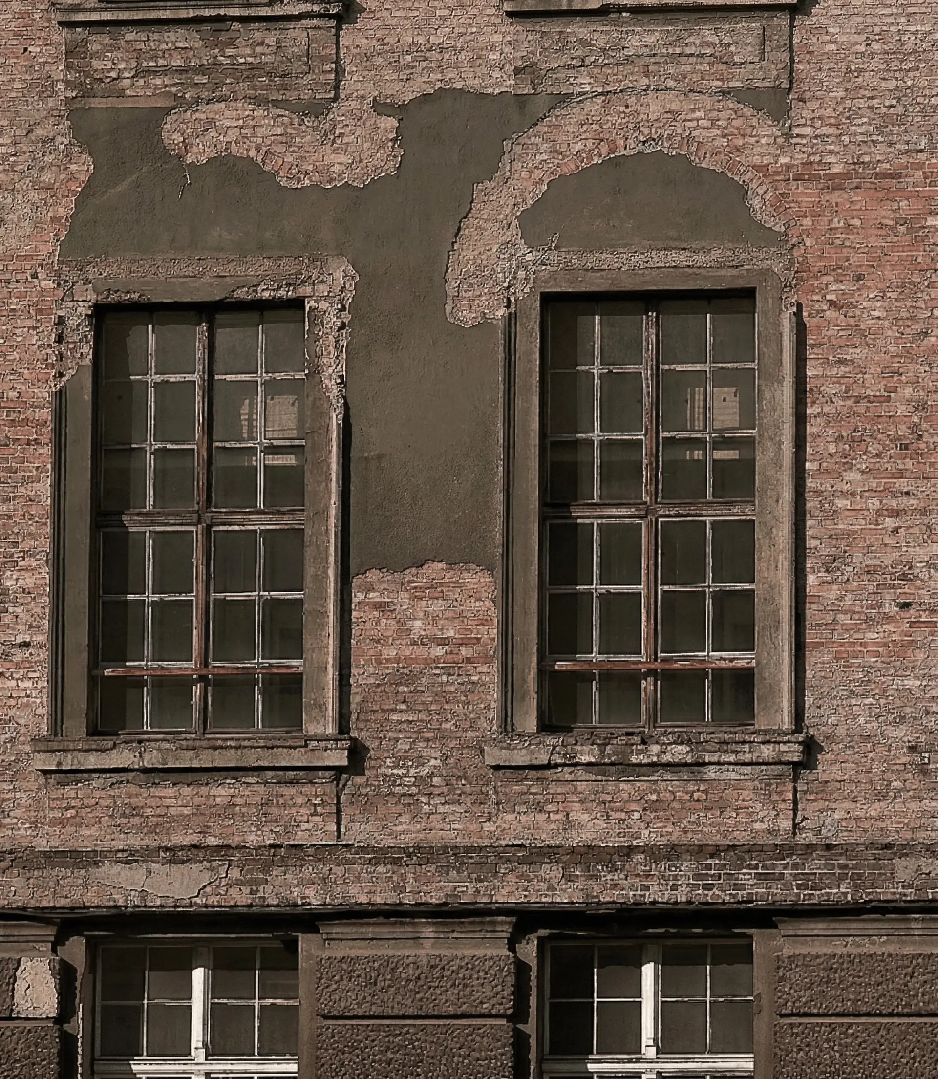 Heritage facade in weathered brick and repaired plaster — honest materials aging with dignity