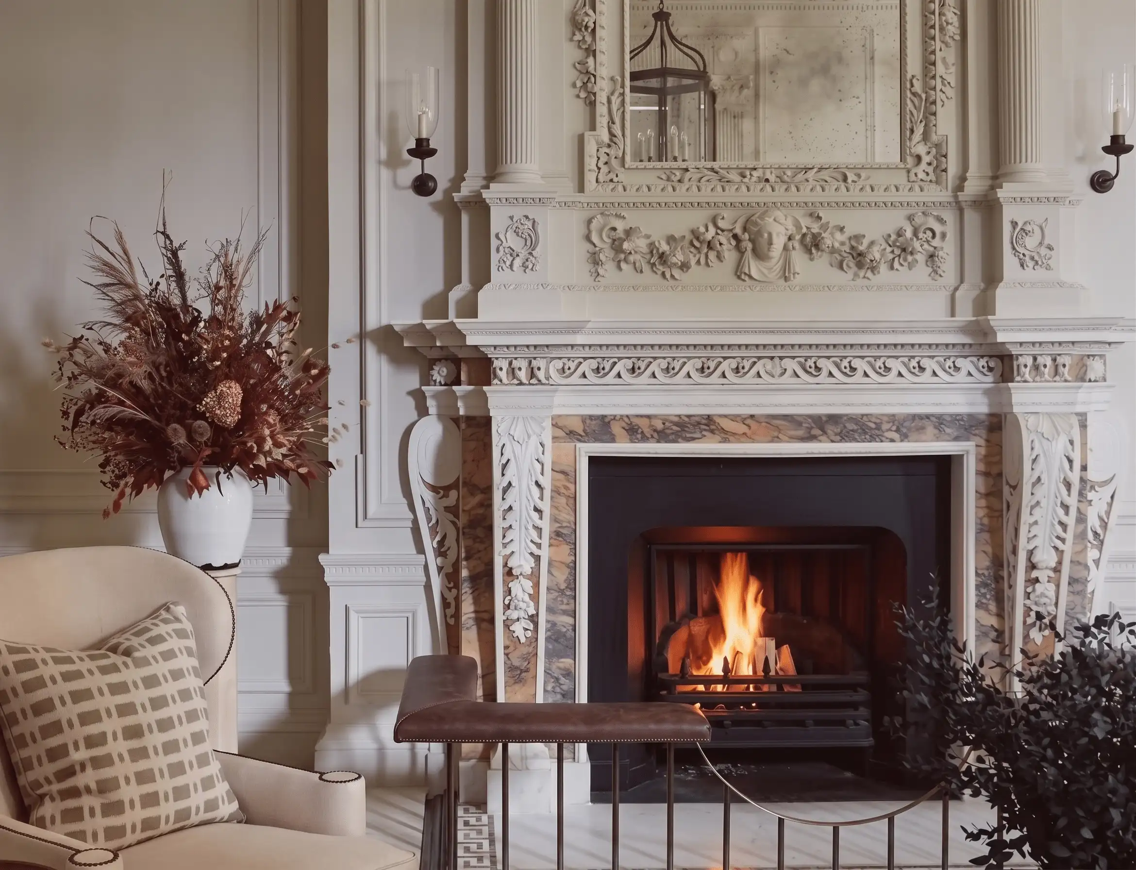 English traditional fireplace with ornate stone hearth, panelled walls, antique mirror, brass candlesticks, and a layered Persian rug — the architectural centre of an English country drawing room