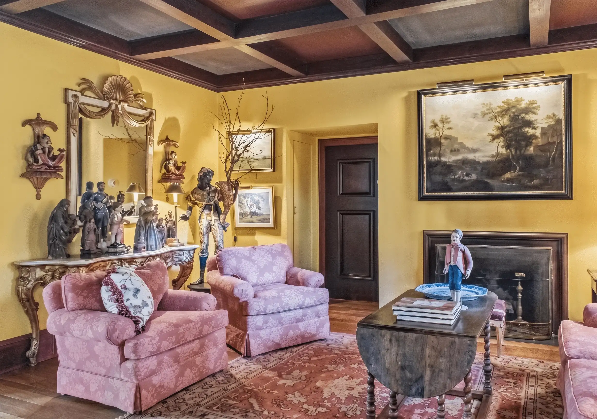 English traditional gallery wall with layered framed oil portraits, equine paintings, botanical prints, and brass picture lights — a collected interior built over time, not assembled at once