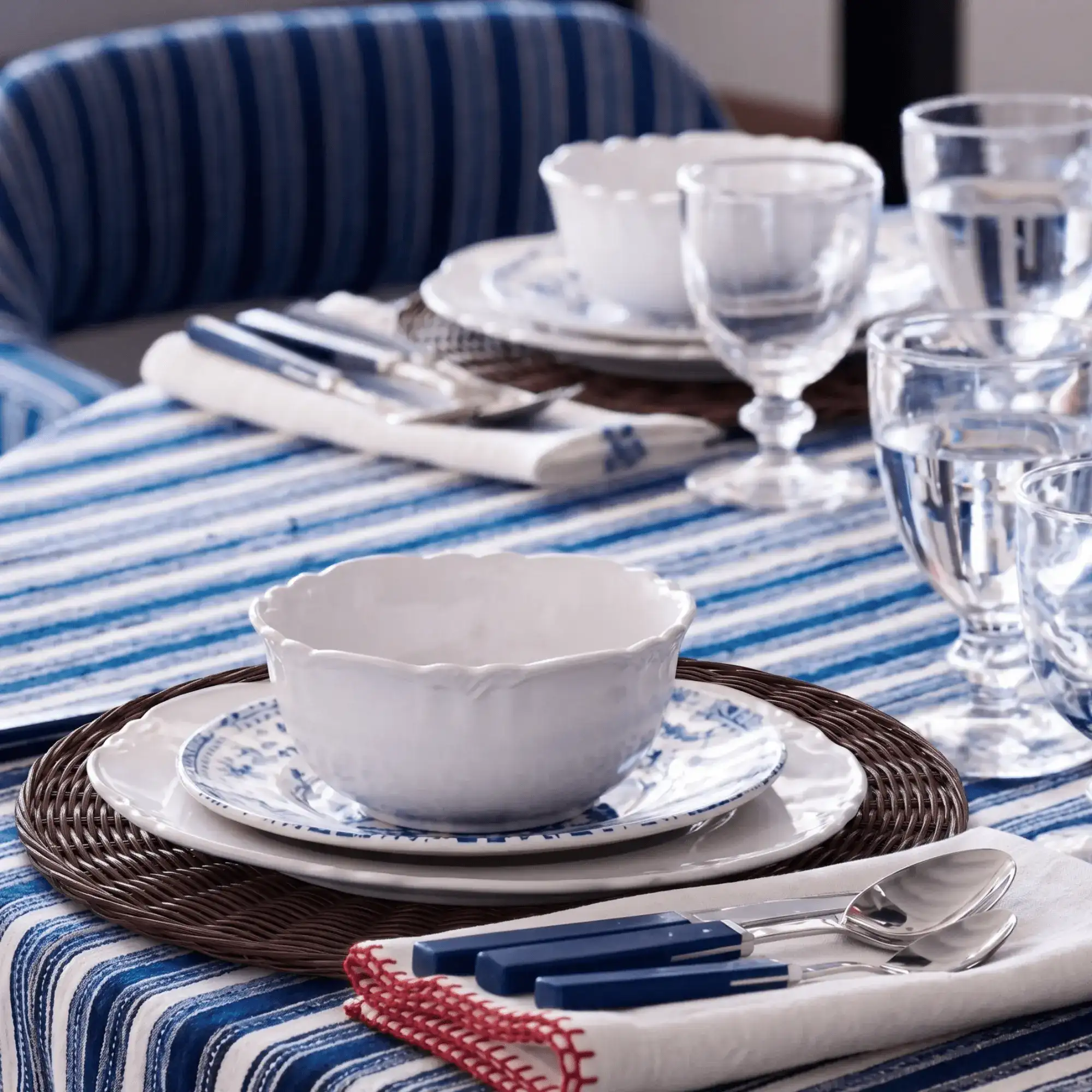 Montecito Round Rattan Placemat 2 Montecito Round Rattan Placemat layered beneath ceramic dinnerware on a blue striped dining table