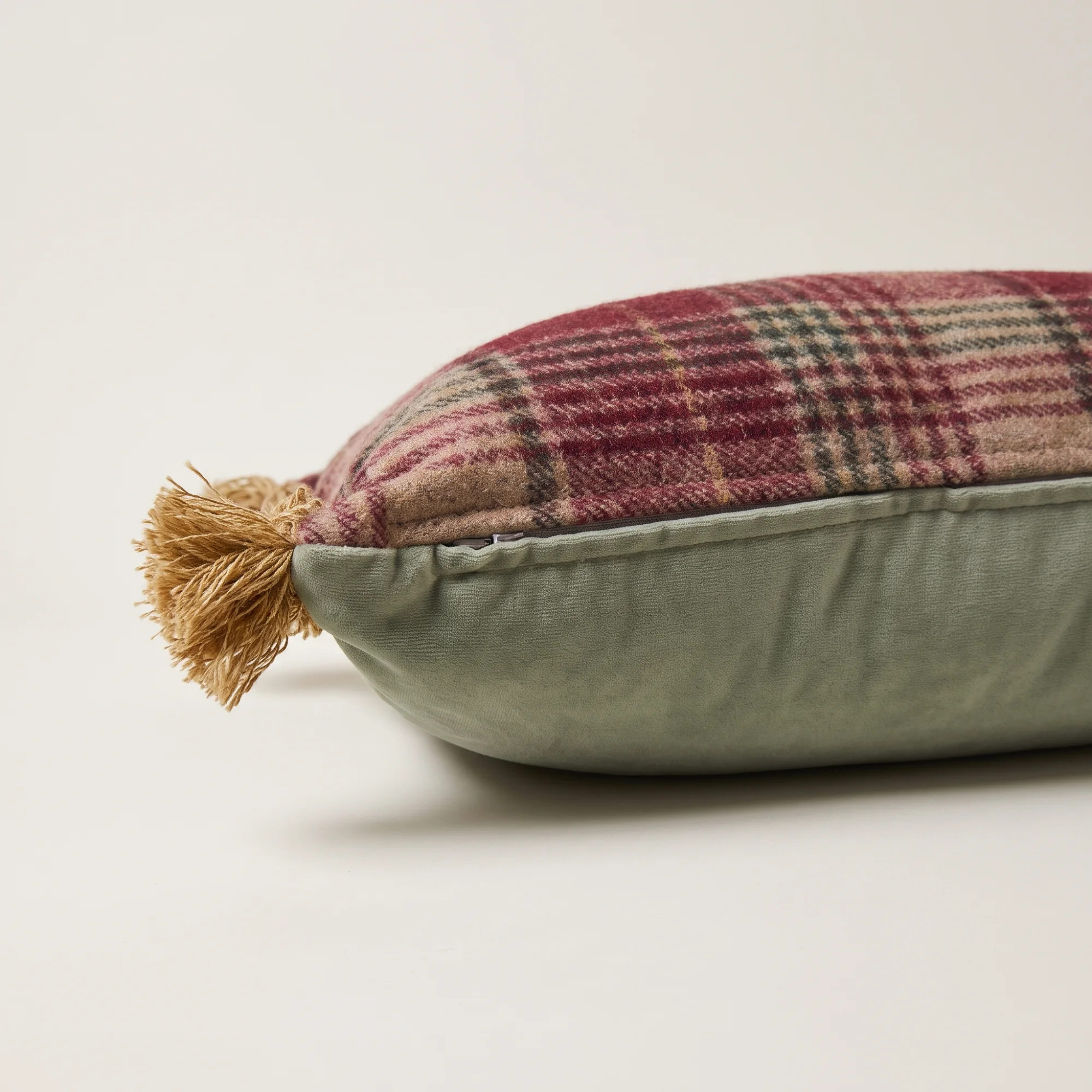 Falkirk Plaid Lumbar Throw Pillow 3 The Falkirk Plaid Lumbar Throw Pillow side view showing the sage-green velvet back and a gold fringe corner